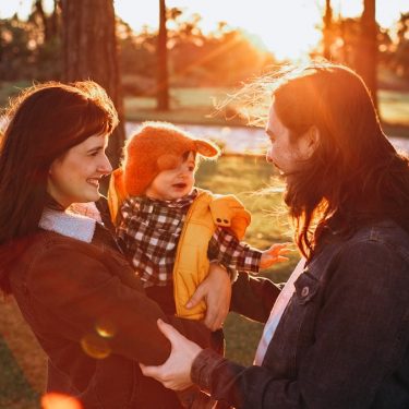 woman in black jacket carrying baby in white and black checkered dress shirt during daytime